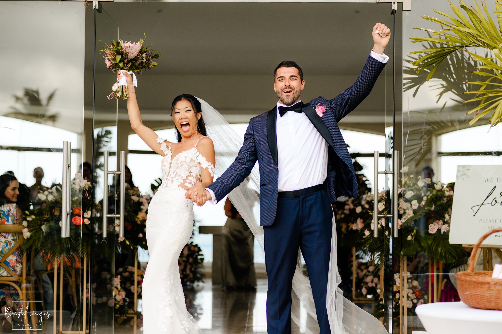 Joyful just married couple celebrating their destination wedding ceremony exit with raised arms