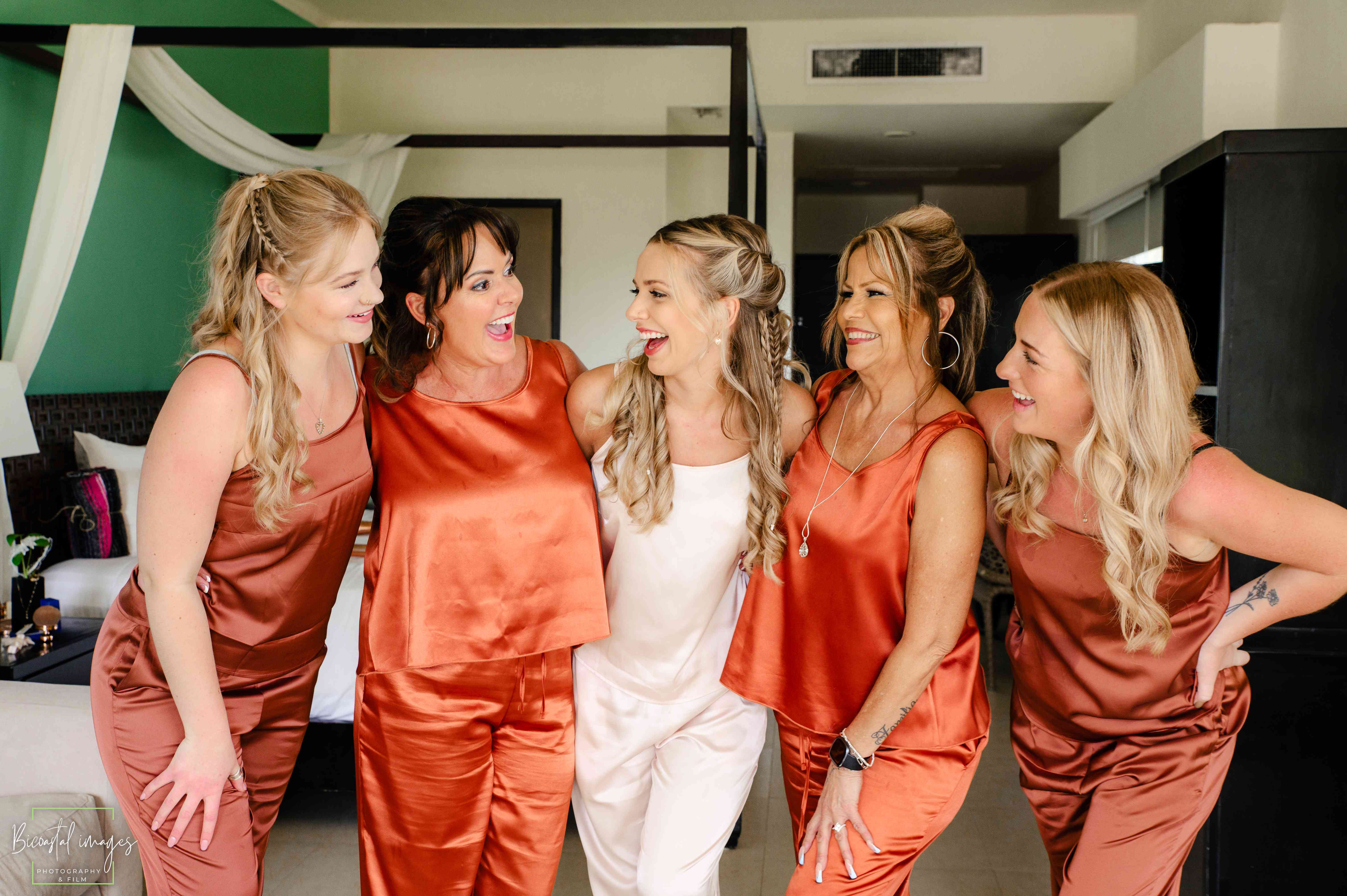 Bridal party with bride in white and bridesmaids in rust orange silk dresses