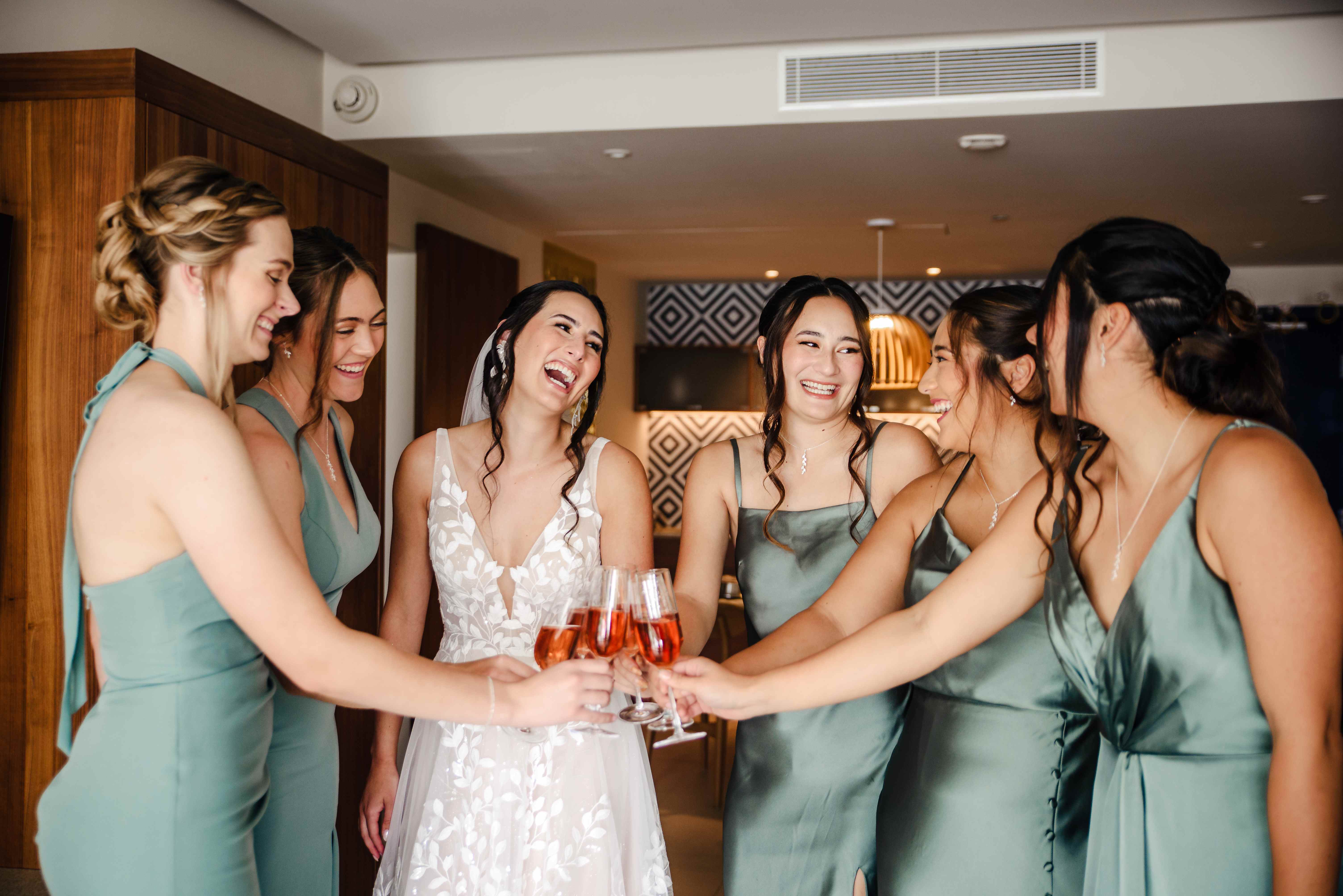 Bridal party toast scene with bride and bridesmaids in sage green dresses