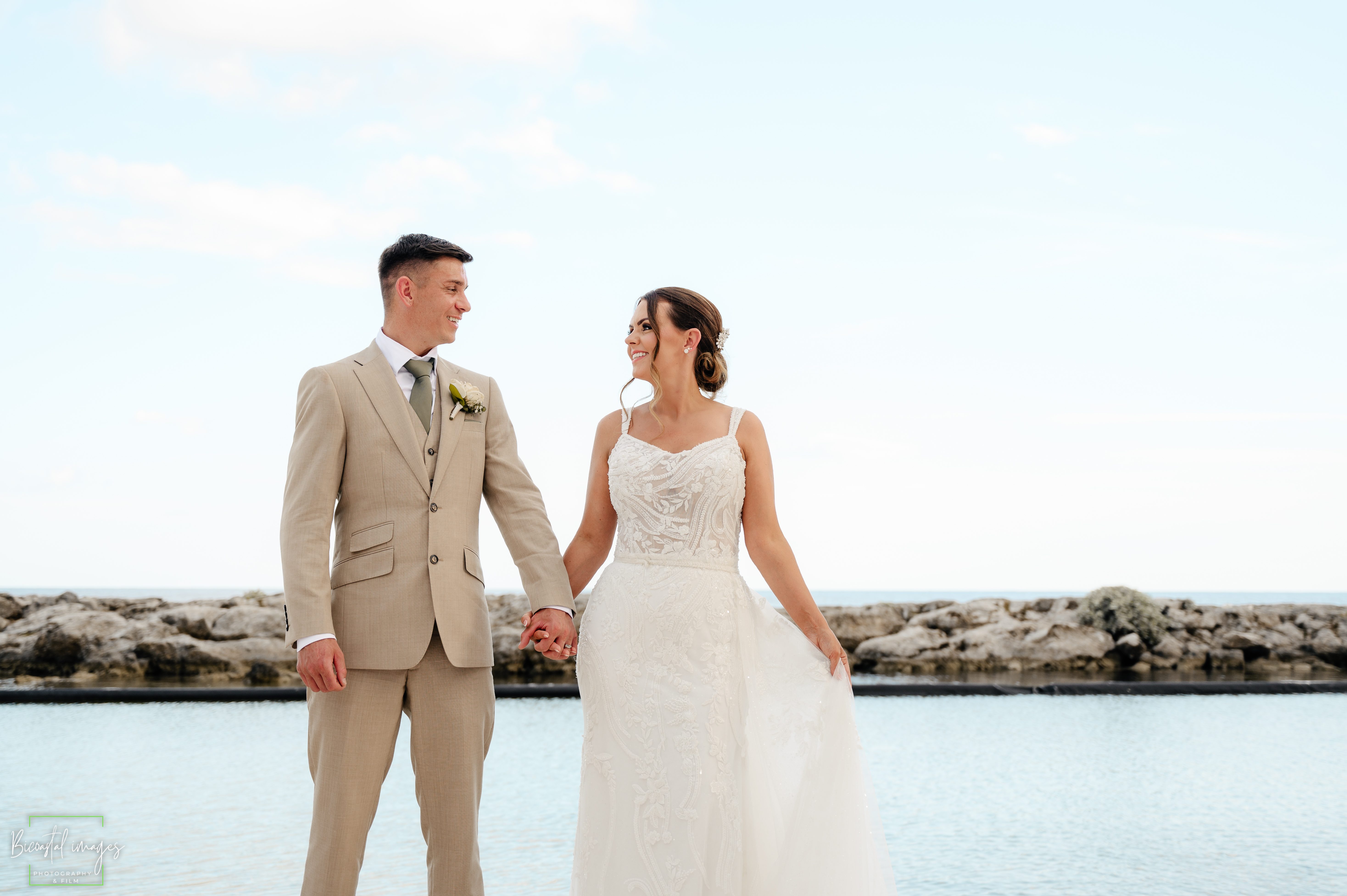 Bride and groom holding hands gazing at each other by the Caribbean sea during couples portrait session at Riviera Maya destination wedding
