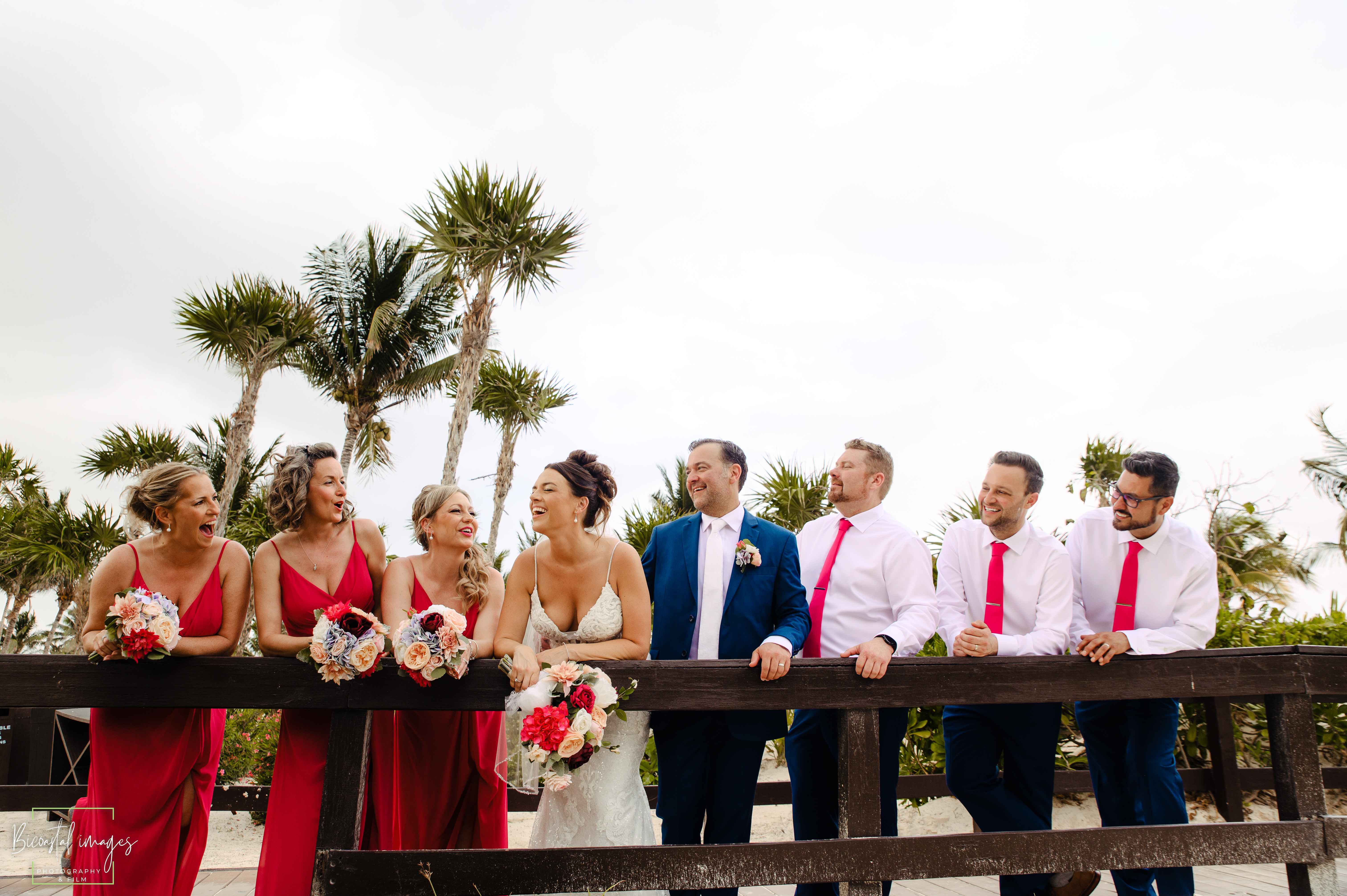 Fun wedding party photo with bridesmaids in red dresses and groomsmen